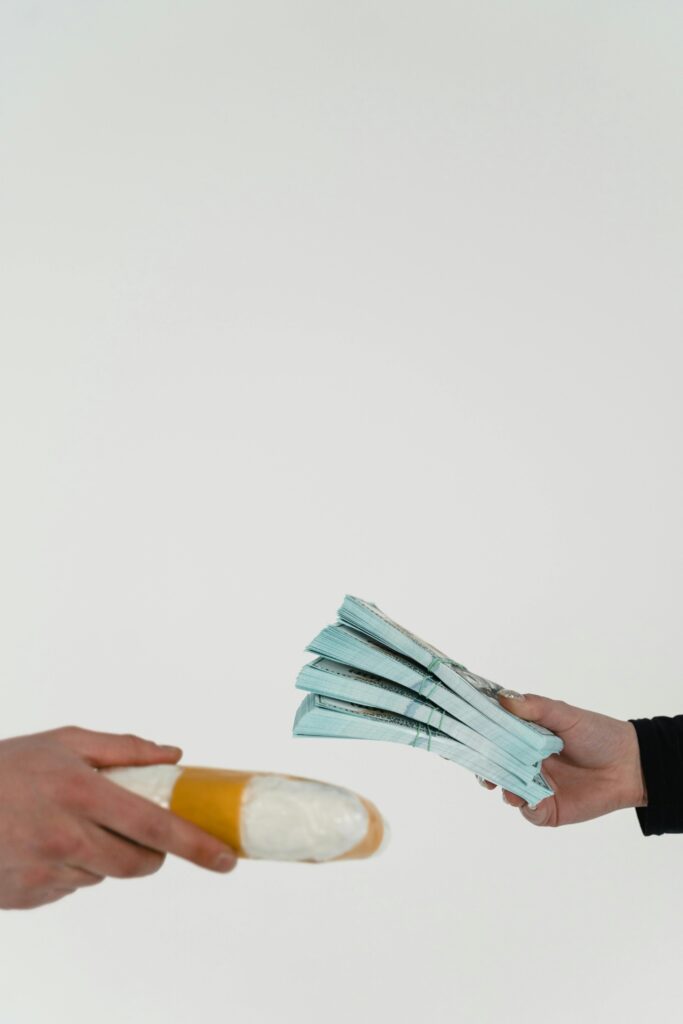 Close-up of hands exchanging cash and a wrapped package in a business transaction.